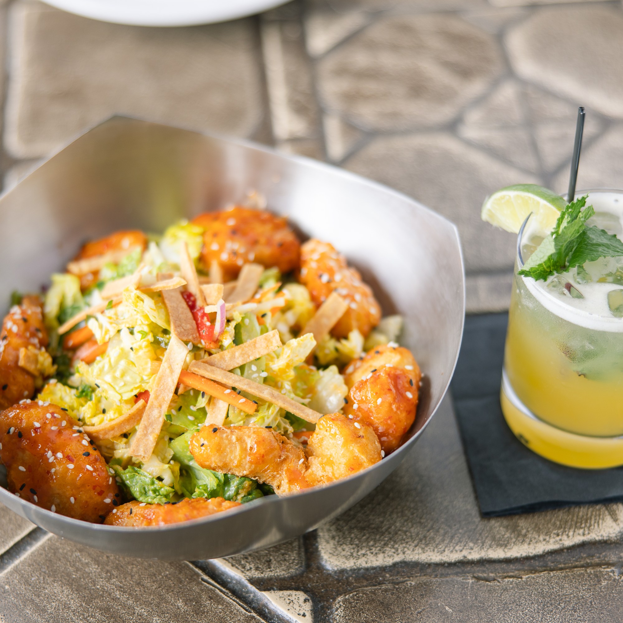 A salad with crispy tempura chicken and wonton pieces served with a refreshing cocktail at The Hill Tavern Bar & Grill at Galloping Hill Golf Course in Kenilworth, NJ.