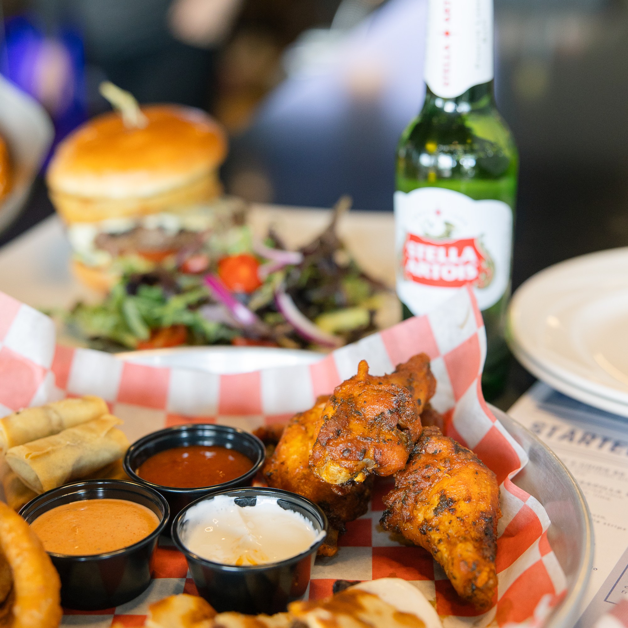 A sampler platter with wings, quesadilla pieces, onion rings, spring rolls, and dips and a burger with a side salad served with a beer at The Hill Tavern Bar & Grill at Galloping Hill Golf Course in Kenilworth, NJ.