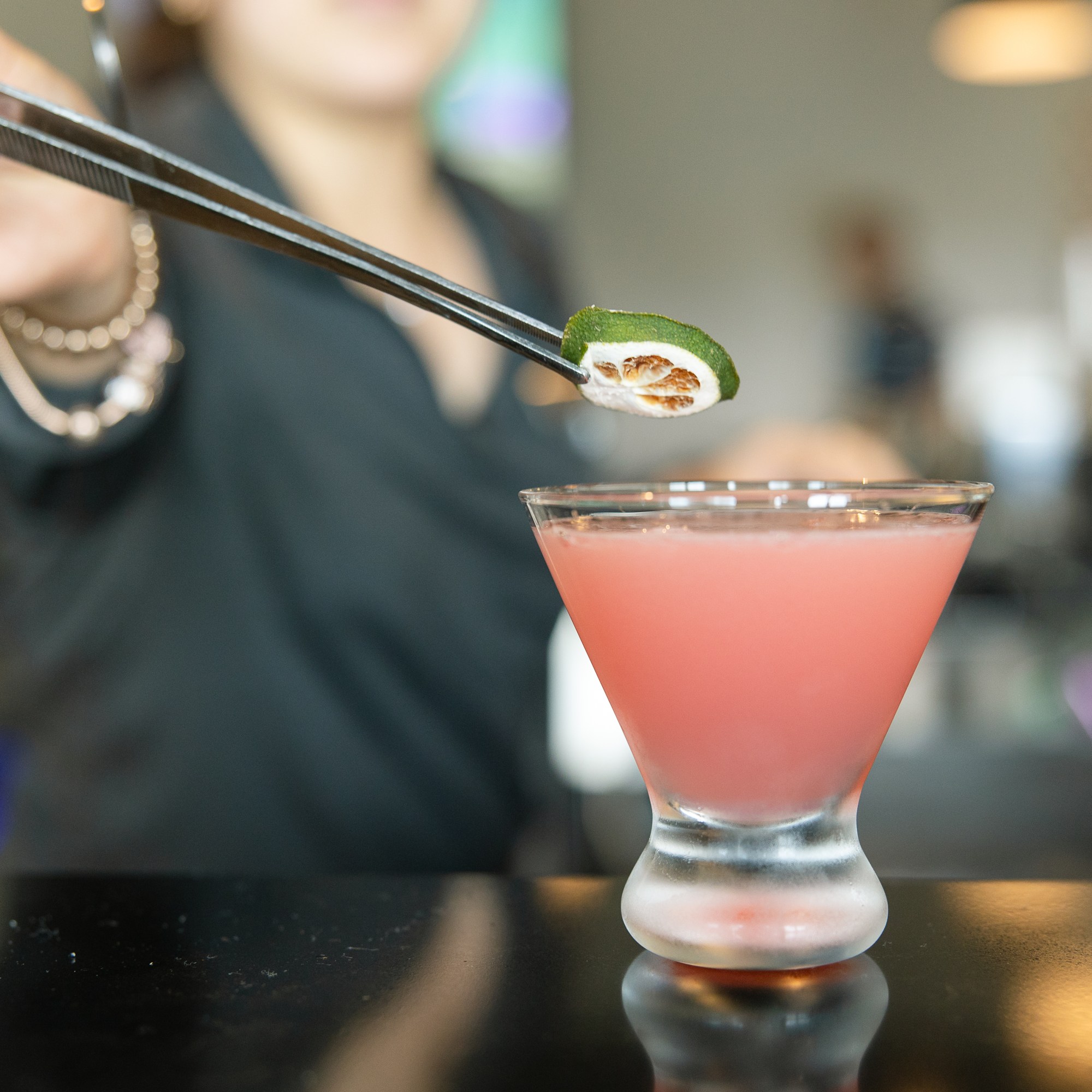 A server placing a dried lime on a Cosmo with tweezers at The Hill Tavern Bar & Grill at Galloping Hill Golf Course in Kenilworth, NJ.