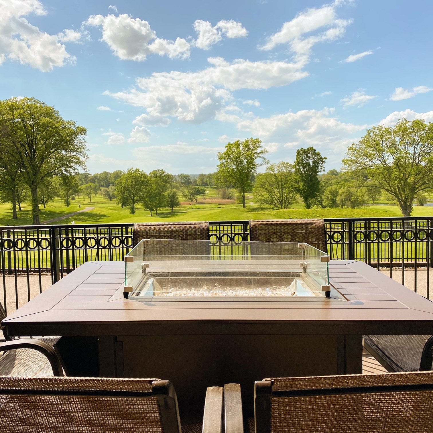 An outdoor patio table with a firepit looking out at the golf course at The Hill Tavern Bar & Grill at Galloping Hill Golf Course in Kenilworth, NJ.